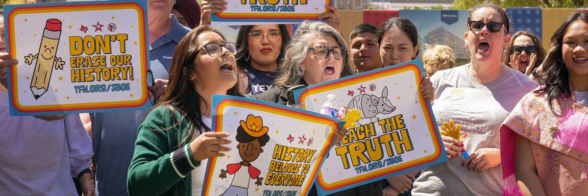 People hold signs reading "tech the truth" and "don't erase our history" during a protest in Austin