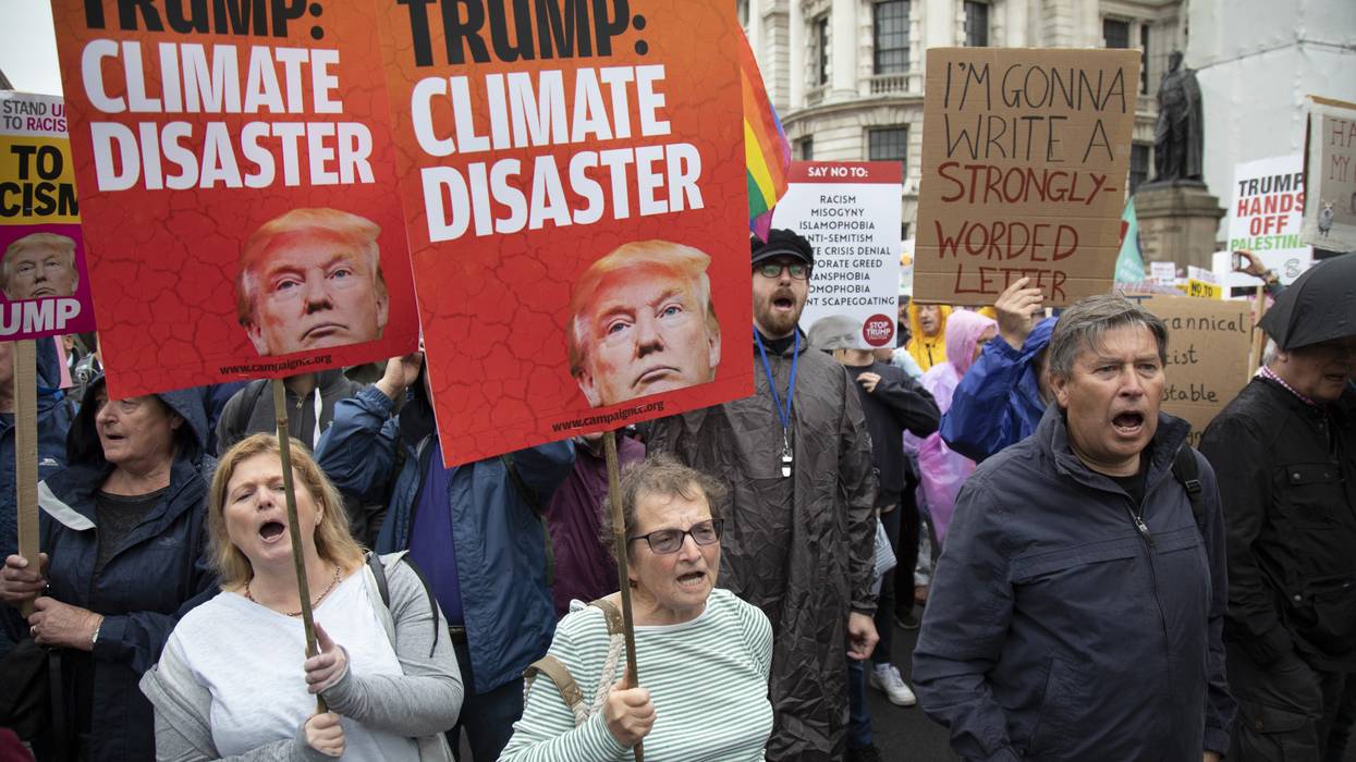 People hold signs reading, "Trump: Climate Disaster."