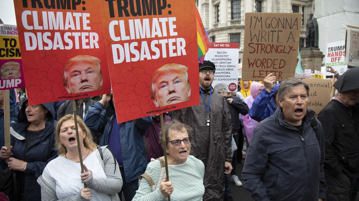 People hold signs reading, "Trump: Climate Disaster."