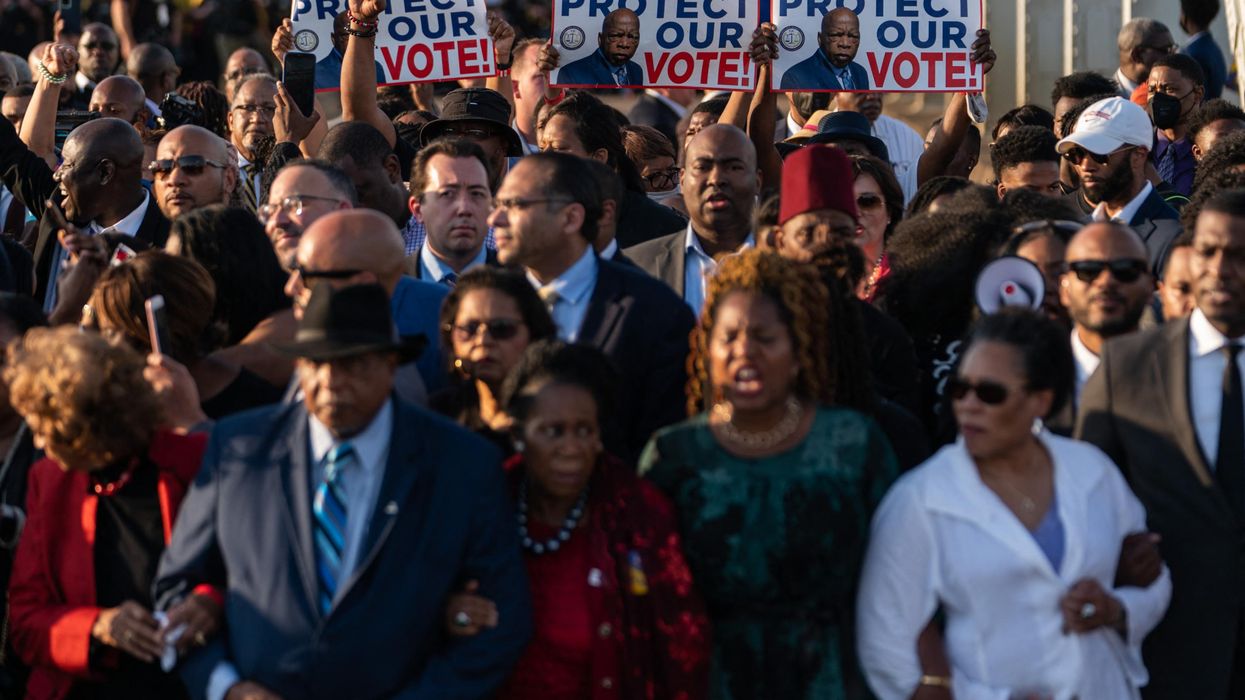 People hold up 'Protect Our Vote' signs as they march across the Edmund Pettus Bridge in commemoration of the 57th anniversary of 'Bloody Sunday' in Selma, Alabama on March 6, 2022