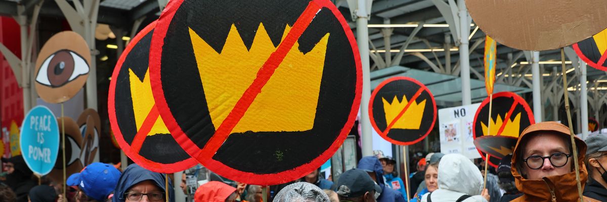 People hold up signs with crowns crossed out at a No Kings protest in New York.