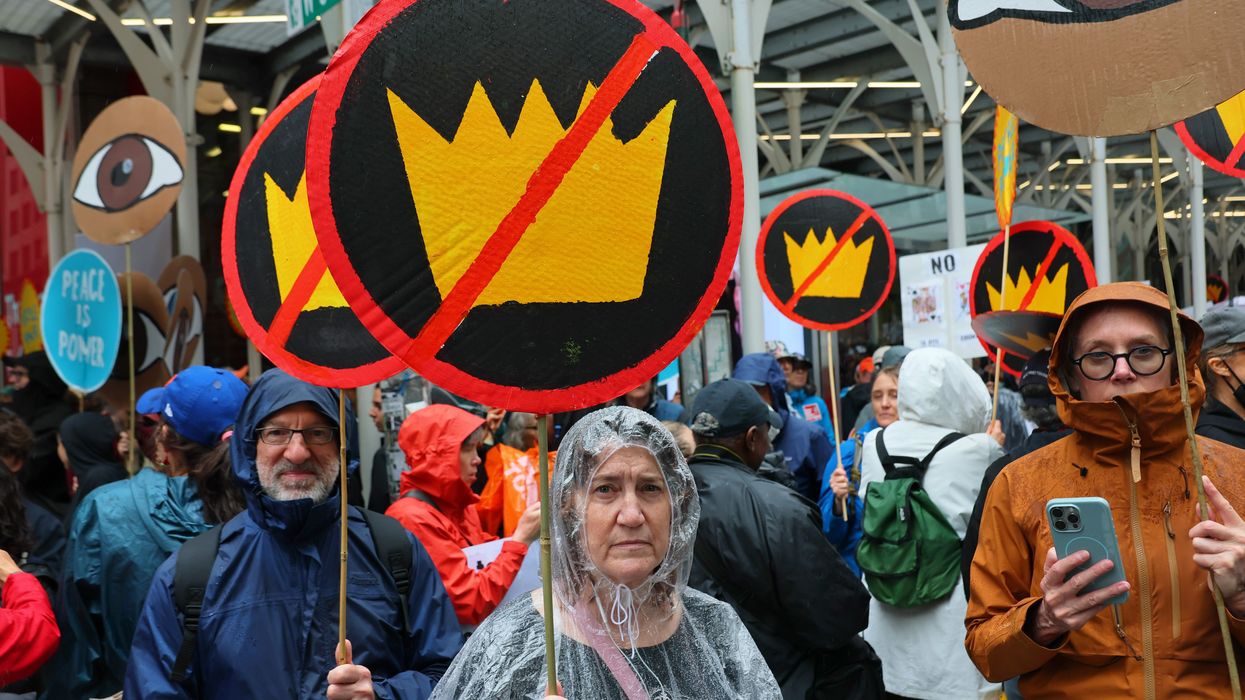 People hold up signs with crowns crossed out at a No Kings protest in New York.