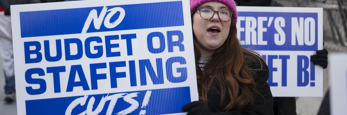 People holding banners and chant during a rally on February 19, 2025