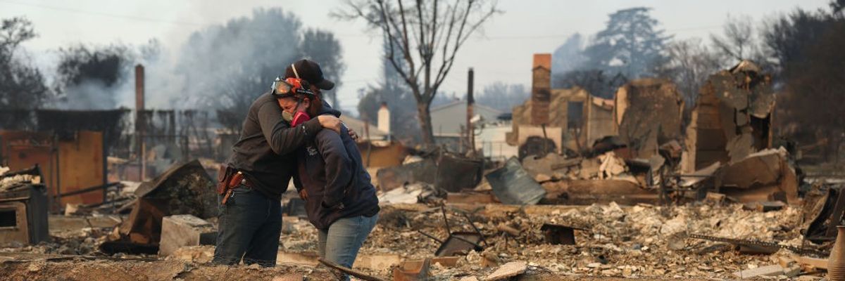 People hug in ruins of home destroyed in LA fires.