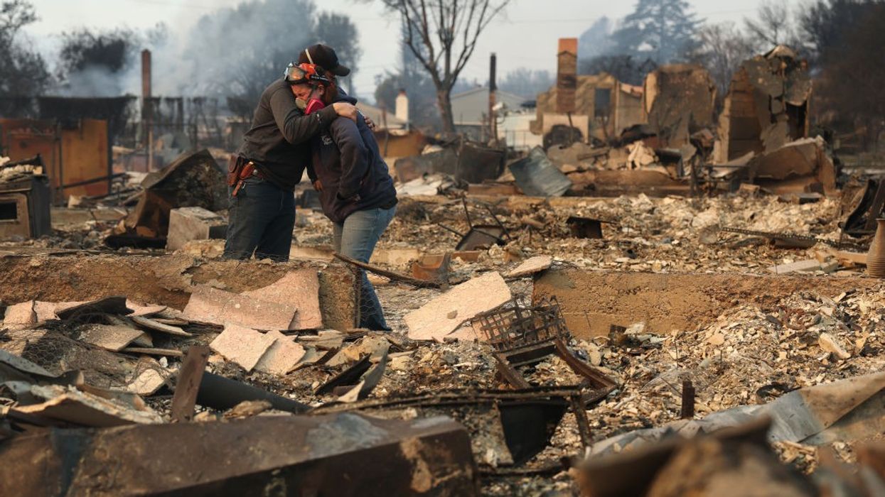 People hug in ruins of home destroyed in LA fires.