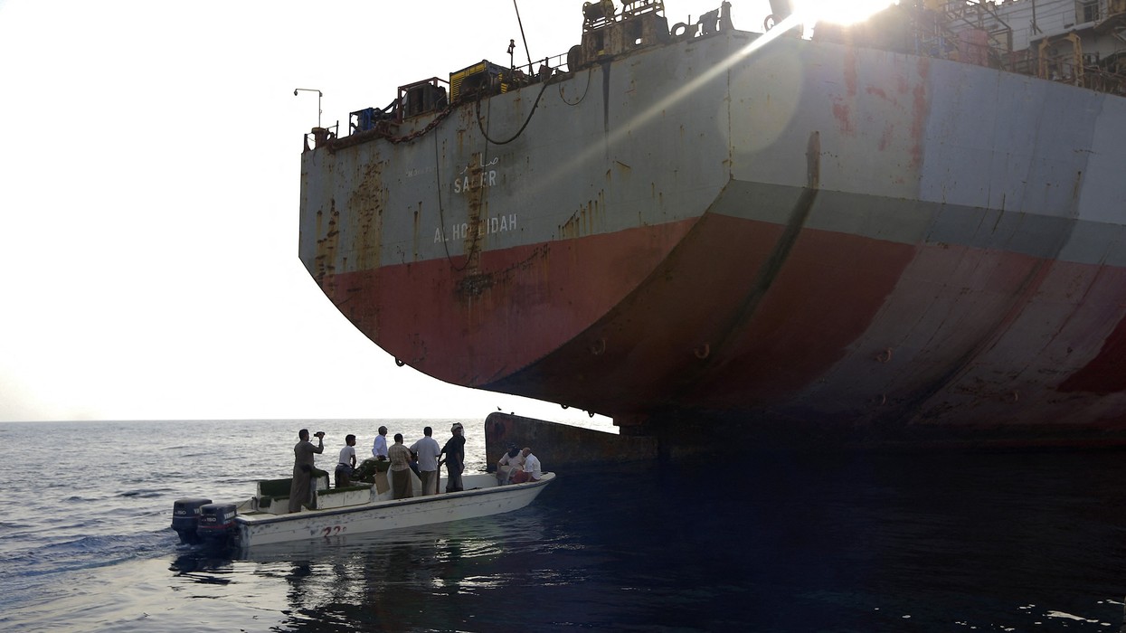 People in a small boat approach the FSO Safer oil tanker