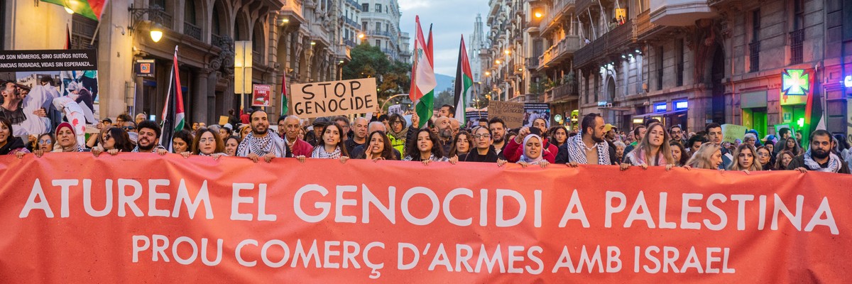 People in Barcelona march with a banner reading "let's stop the genocide in Palestine."