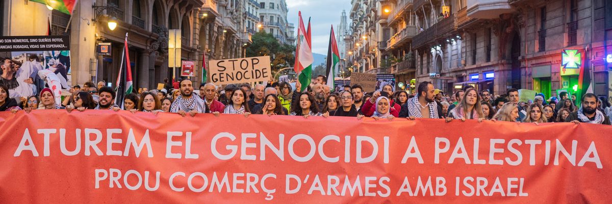 People in Barcelona march with a banner reading "let's stop the genocide in Palestine." 