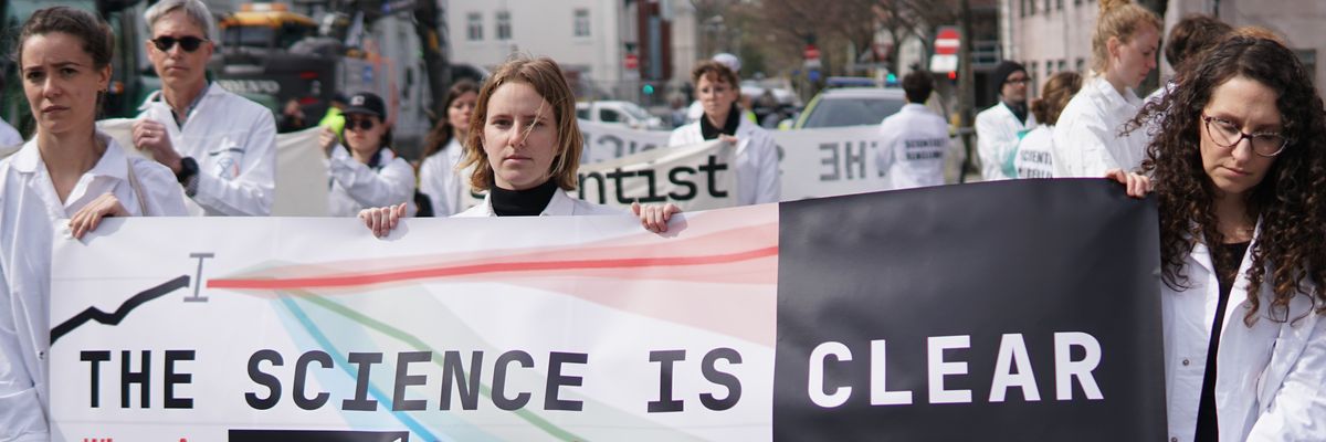 People in white coats hold up a sign.