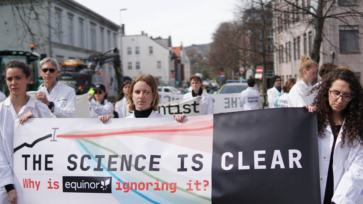 People in white coats hold up a sign.