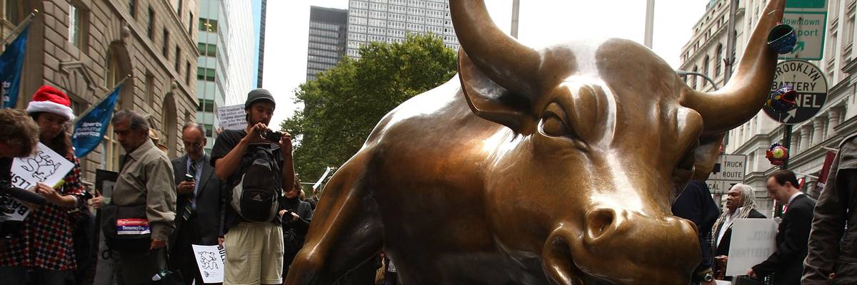 People lay underneath the iconic Wall Street bull during a rally in the financial district against the proposed government buyout of financial firms September 25, 2008 in New York City