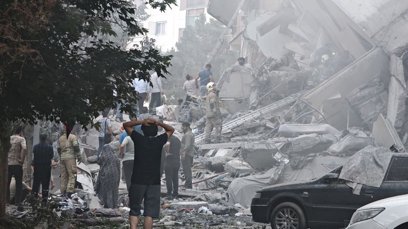 People look at damage in Tehran after Israeli air strikes.
