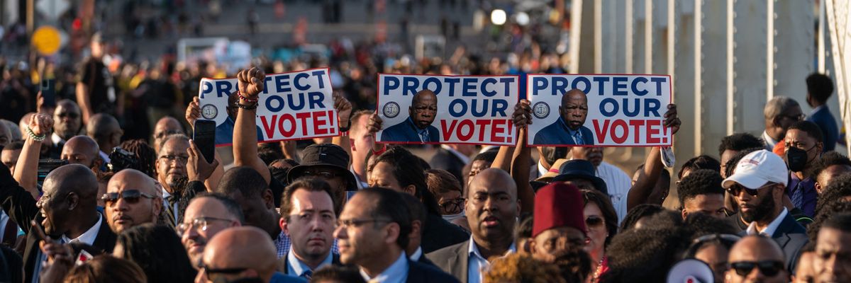 People march across Edmond Pettus Bridge with signs saying, "Protect our vote."