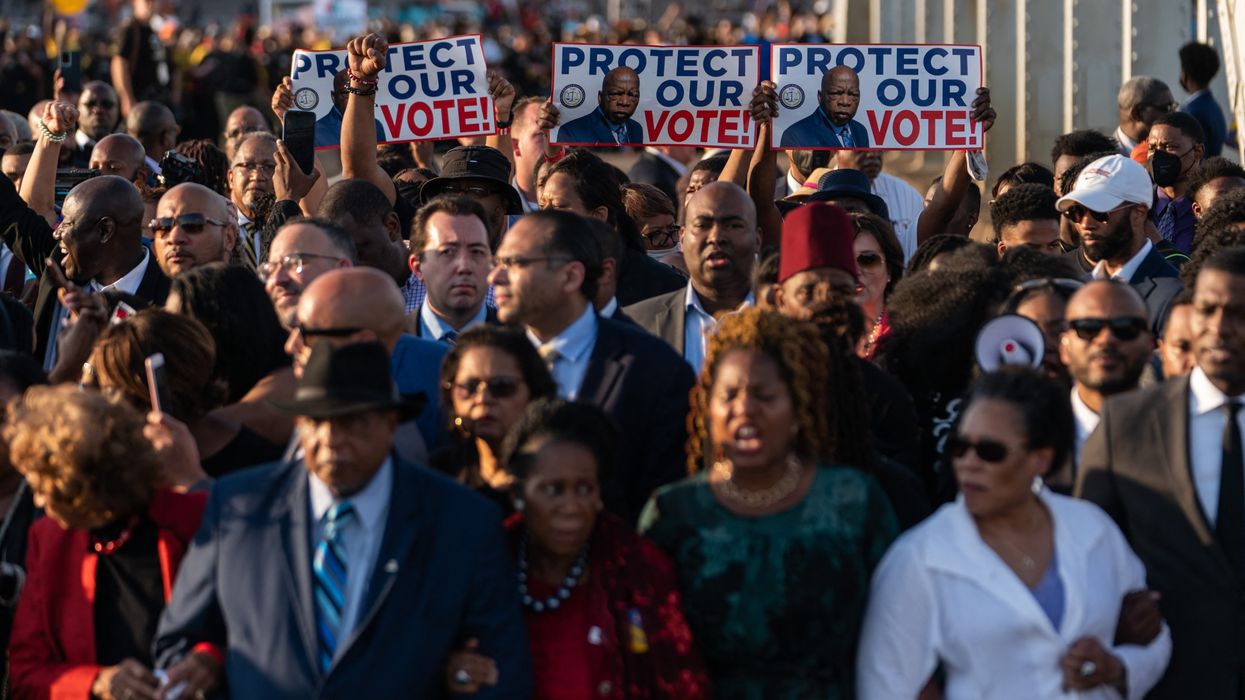 People march across Edmond Pettus Bridge with signs saying, "Protect our vote."