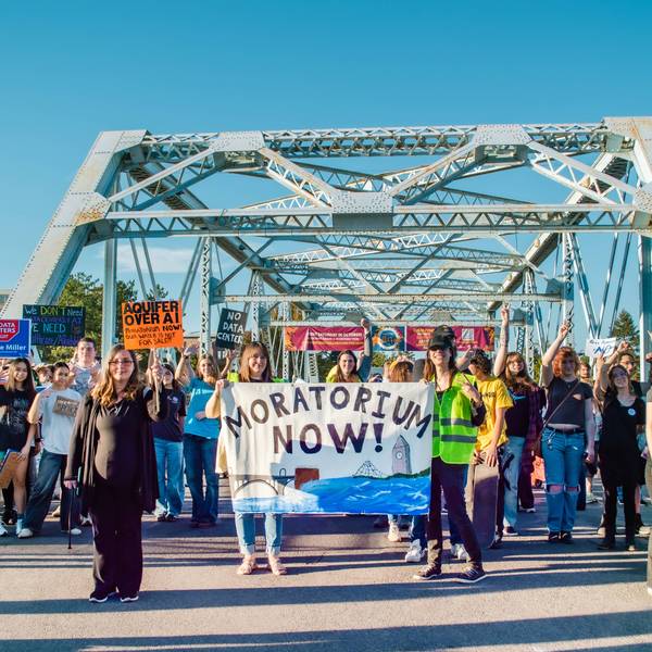 People march on bridge against data centers.