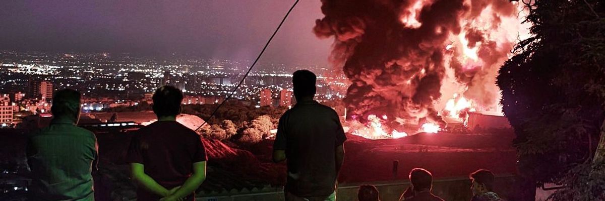 People observe fire and smoke from an Israeli attack on Tehran