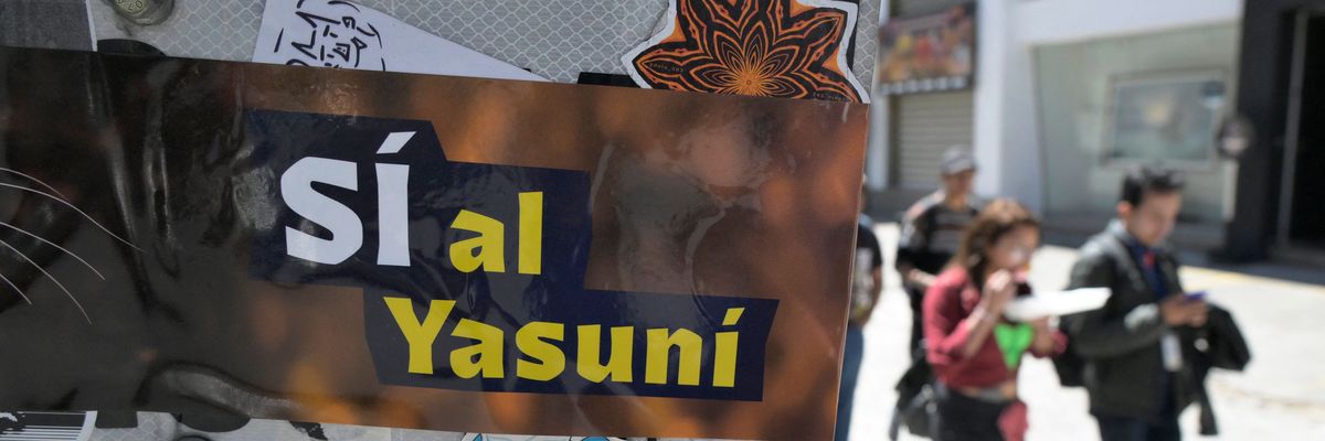 People pass next to an advertisement supporting the halting of the exploitation of crude oil