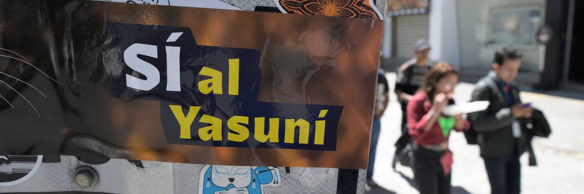 People pass next to an advertisement supporting the halting of the exploitation of crude oil