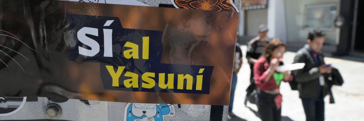 People pass next to an advertisement supporting the halting of the exploitation of crude oil