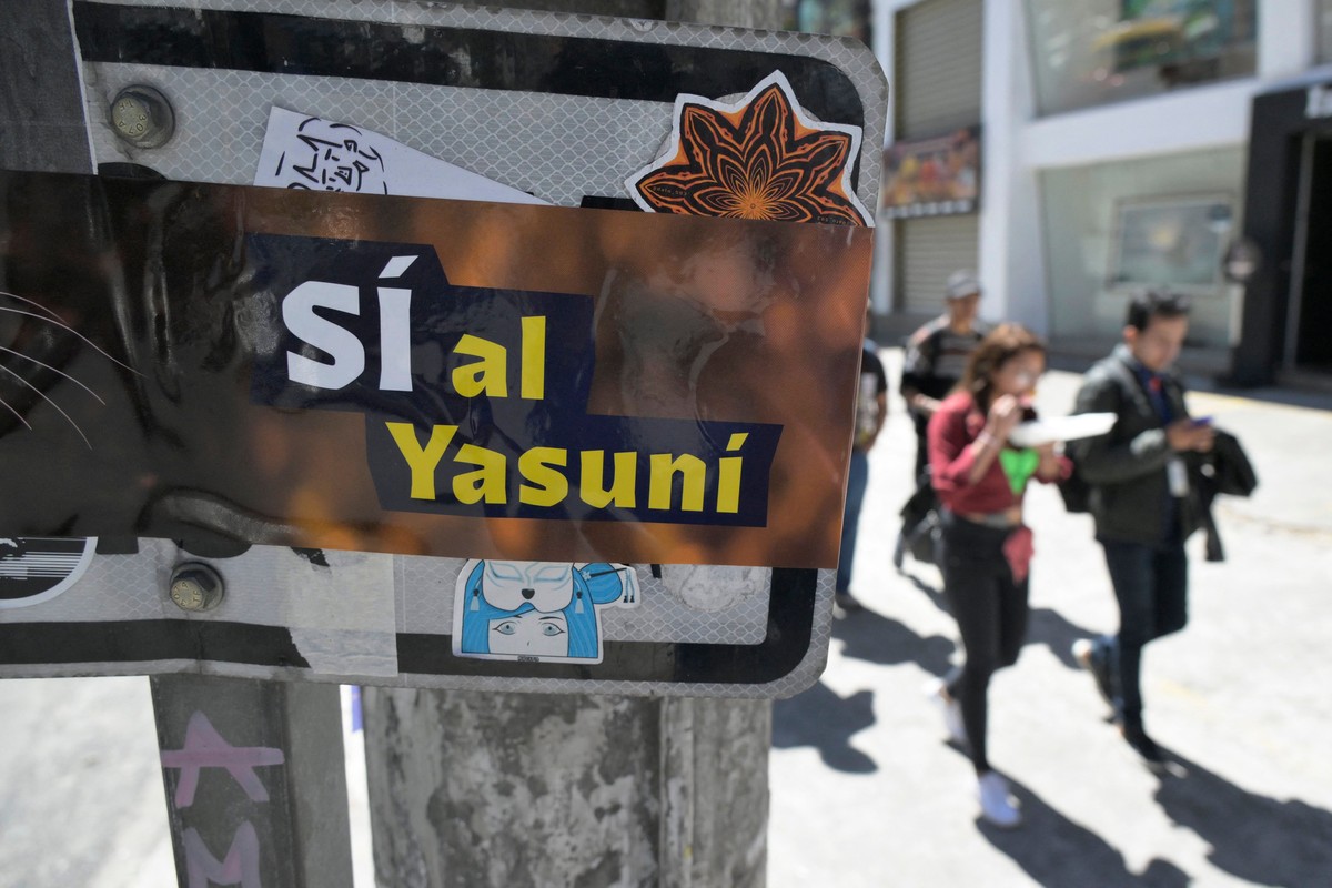 People pass next to an advertisement supporting the halting of the exploitation of crude oil