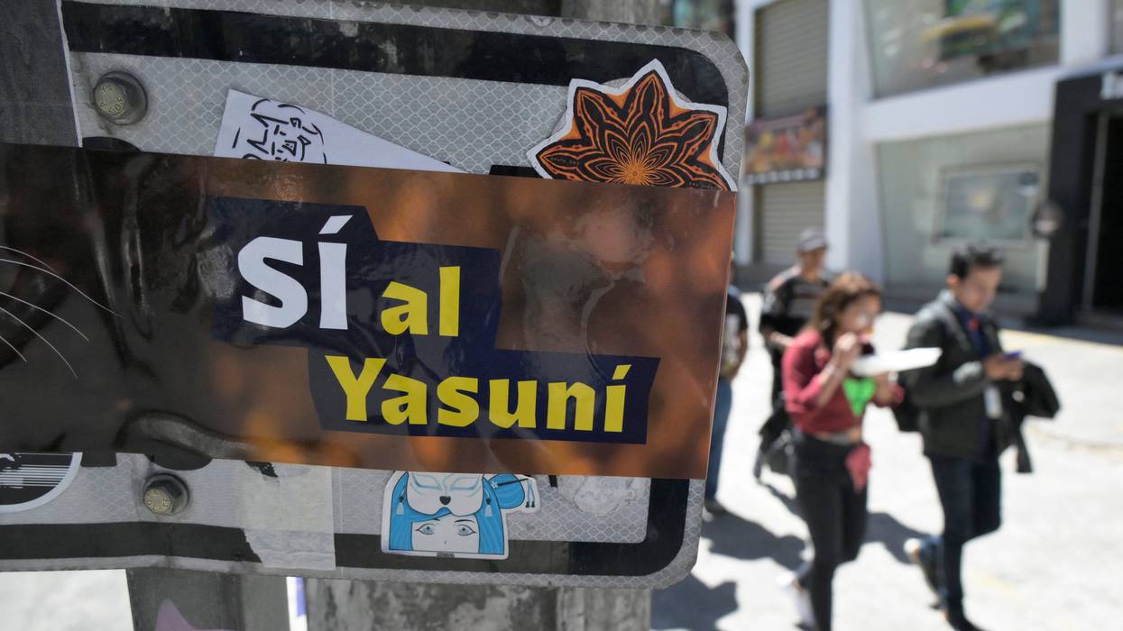People pass next to an advertisement supporting the halting of the exploitation of crude oil