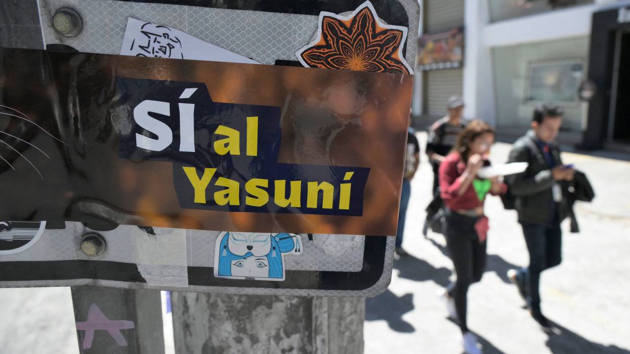 People pass next to an advertisement supporting the halting of the exploitation of crude oil