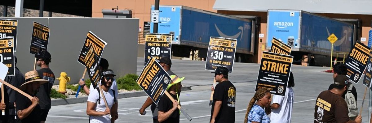 People picket with signs in front of an Amazon warehouse. 