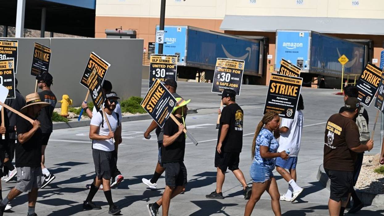 People picket with signs in front of an Amazon warehouse.