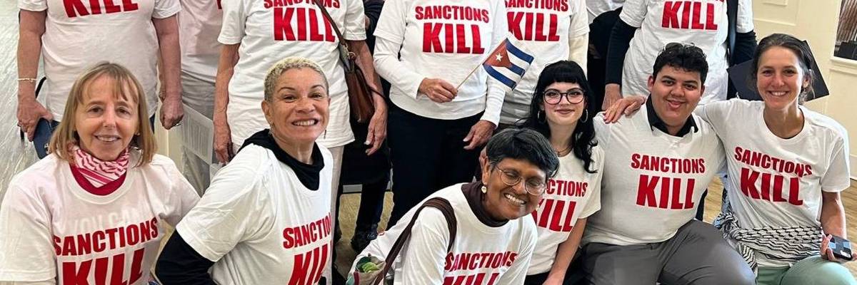 People pose for a photo all wearing a T-shirt reading, "Sanctions kill."