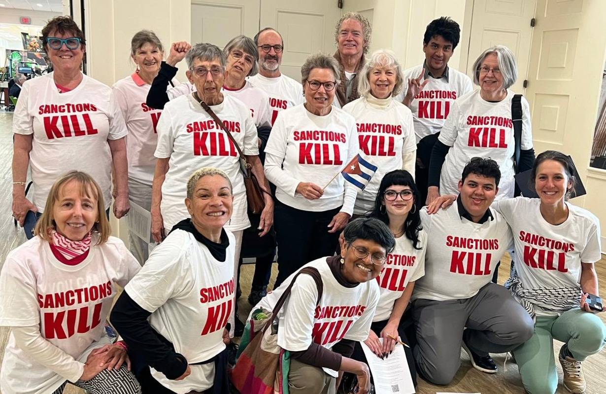 People pose for a photo all wearing a T-shirt reading, "Sanctions kill."