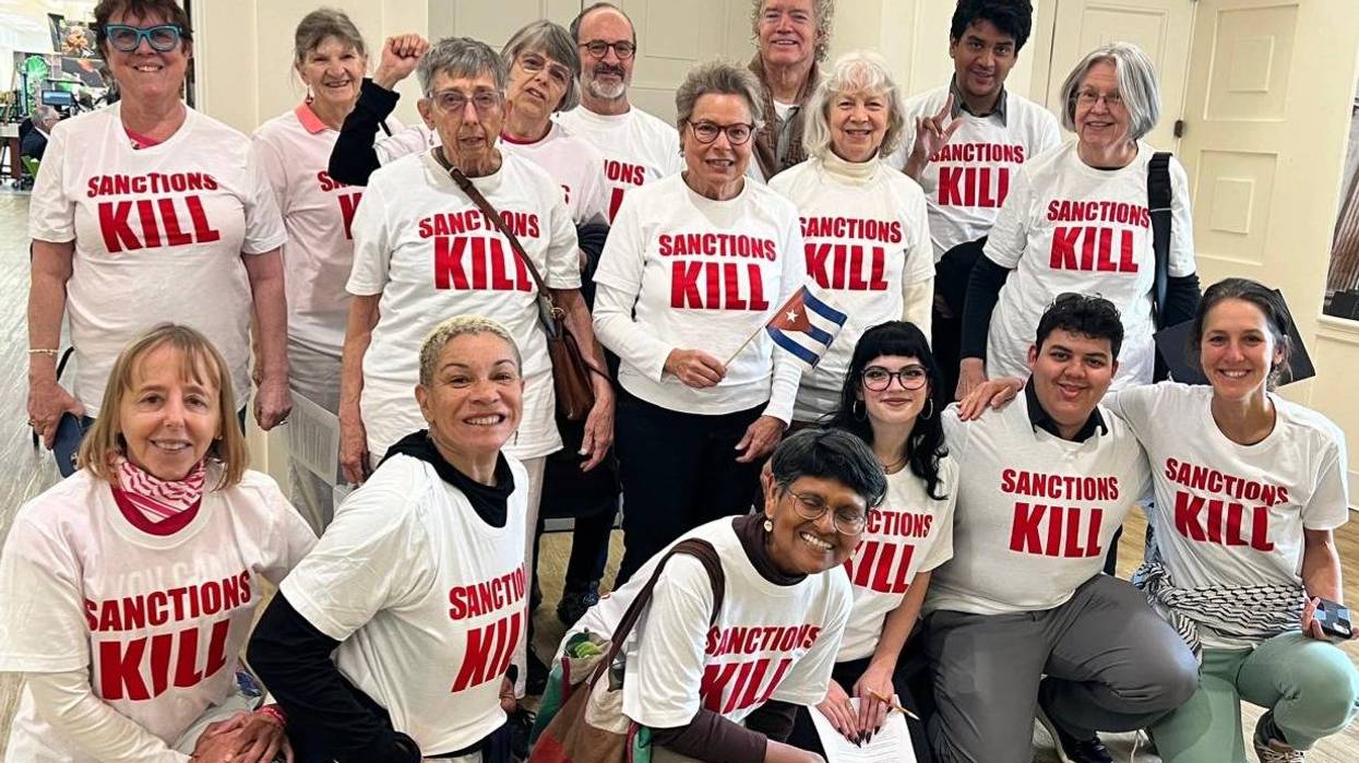 People pose for a photo all wearing a T-shirt reading, "Sanctions kill."