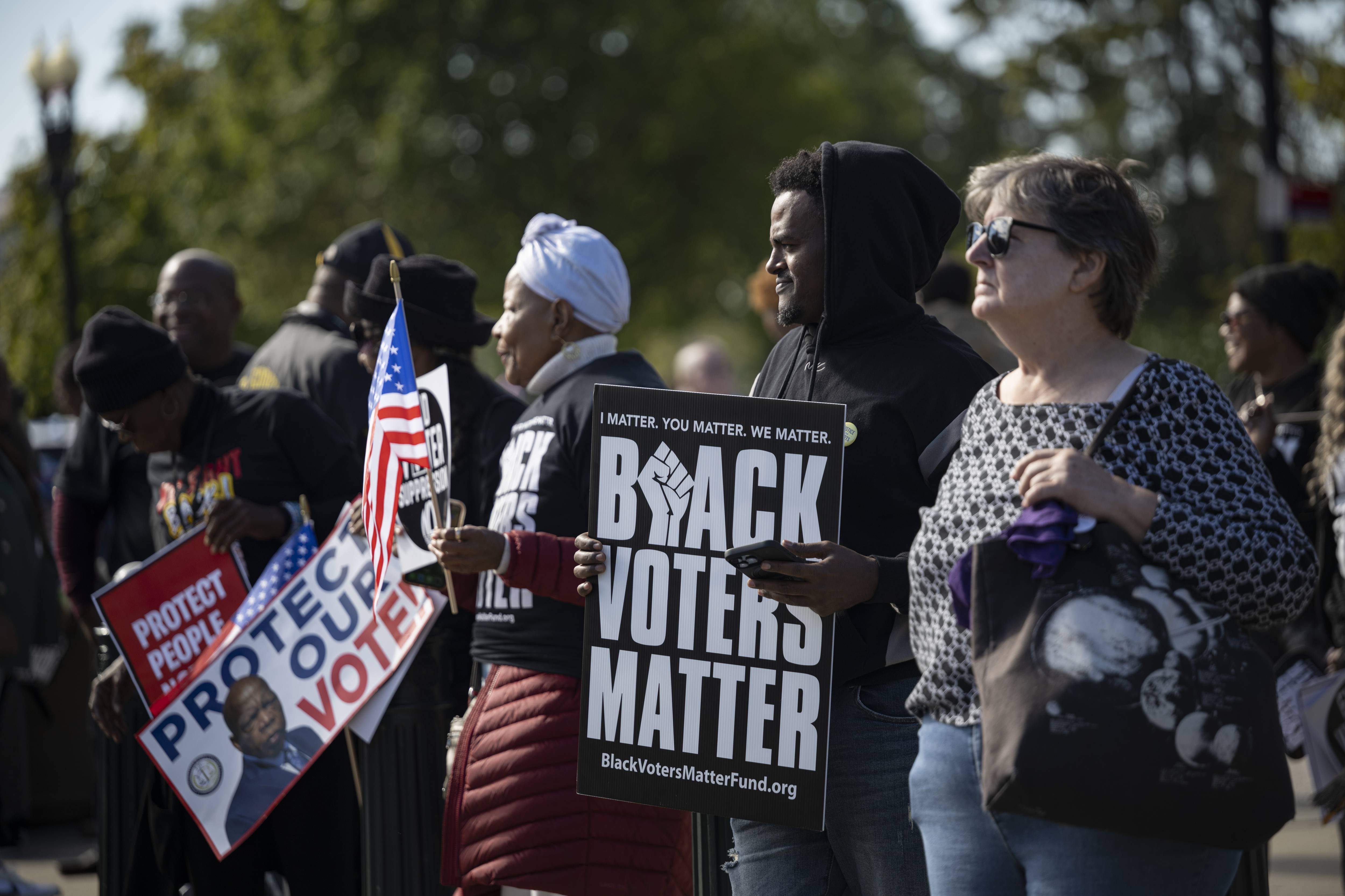 People protest for voting rights; one holds a sign reading "Black voters matter"