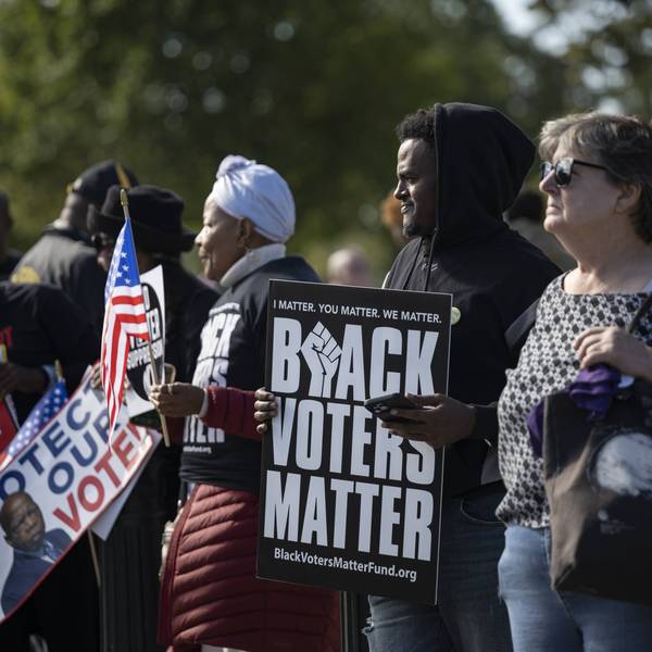 People protest for voting rights; one holds a sign reading "Black voters matter"