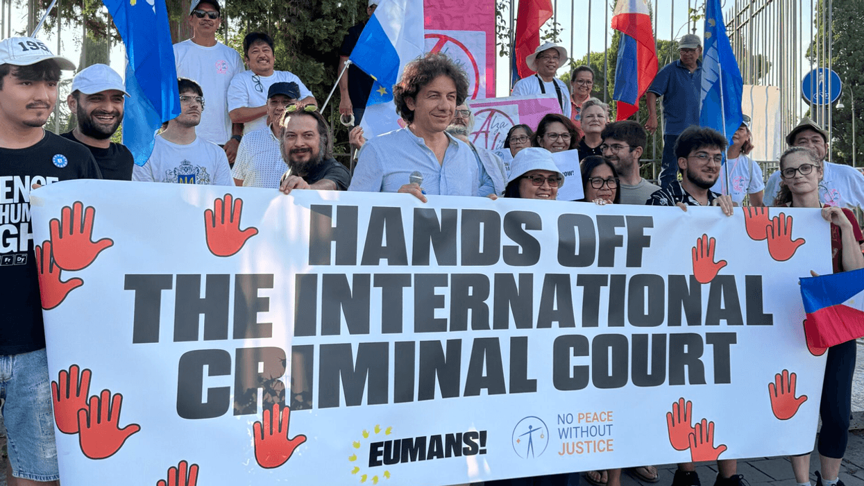 People protest with a sign reading "Hands off the International Criminal Court"
