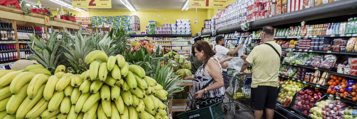 People shop in produce section of supermarket.