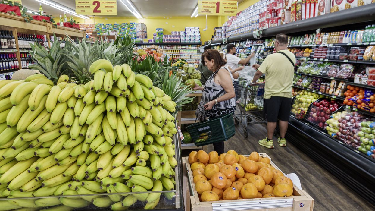 People shop in produce section of supermarket.