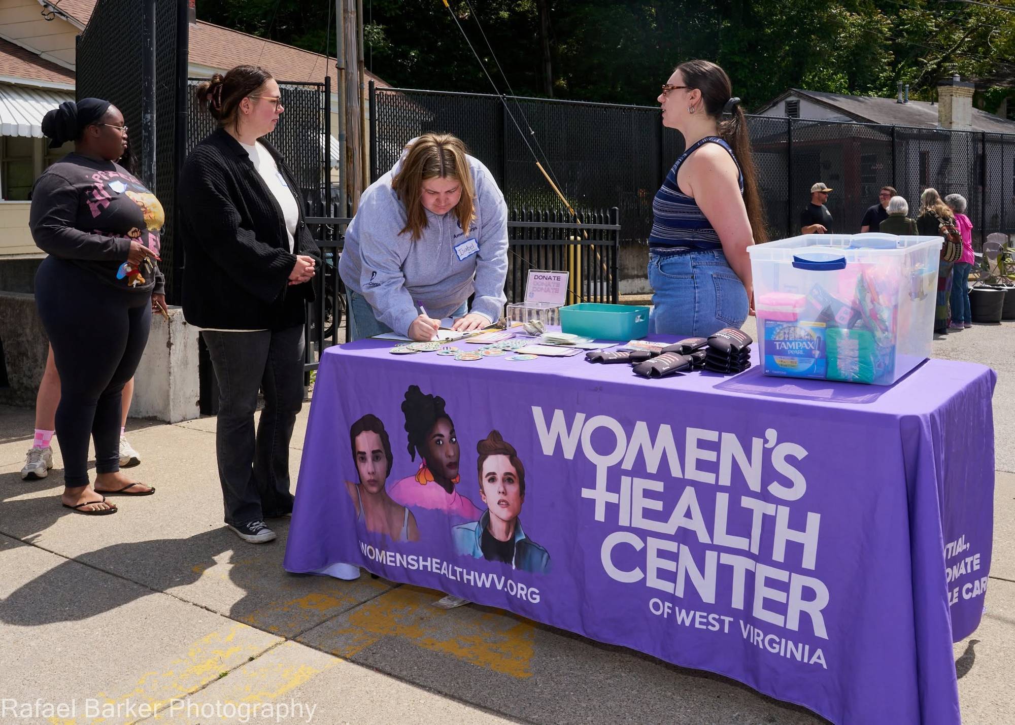 People sign up at a Women's Health Center of West Virginia table.