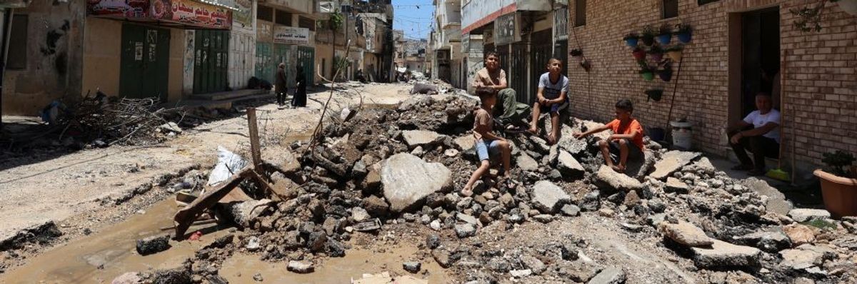 People sit in rubble after the Israeli raid of Jenin.