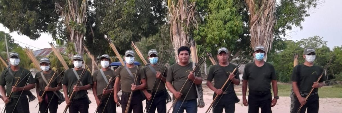 People stand in a line with traditional weapons.