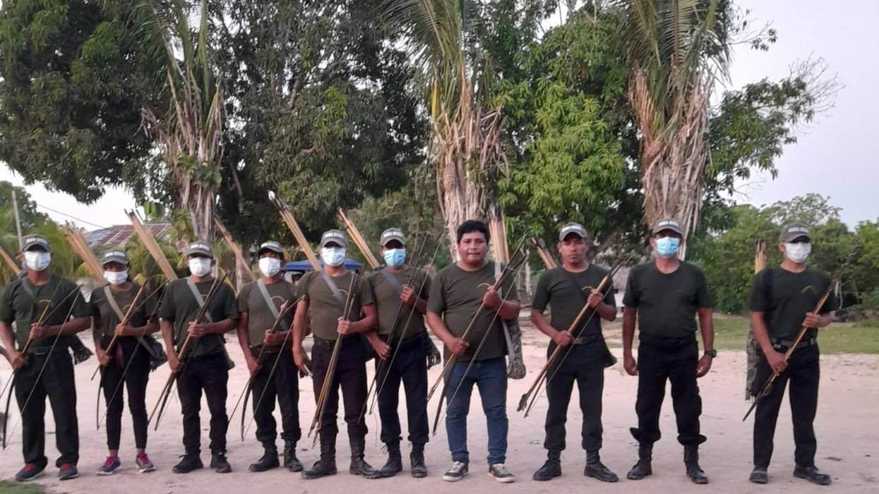 People stand in a line with traditional weapons.