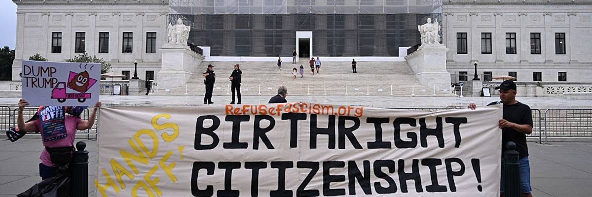 People stand in front of the Supreme Court with a banner reading, "Hands off birthright citizenship."