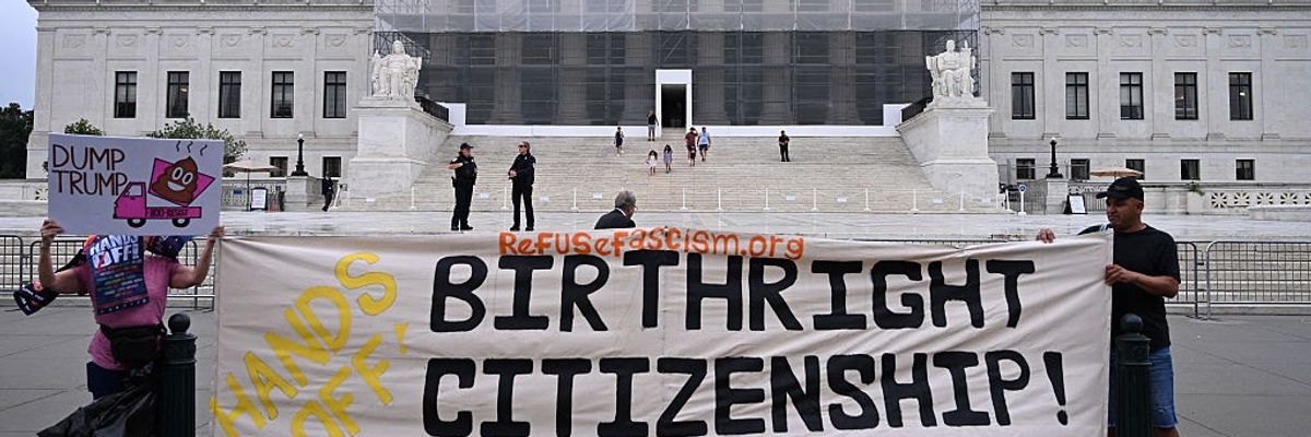 People stand in front of the Supreme Court with a banner reading, "Hands off birthright citizenship."