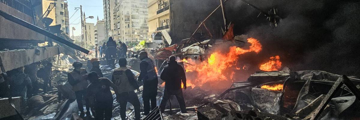 People stand in rubble in Lebanon.