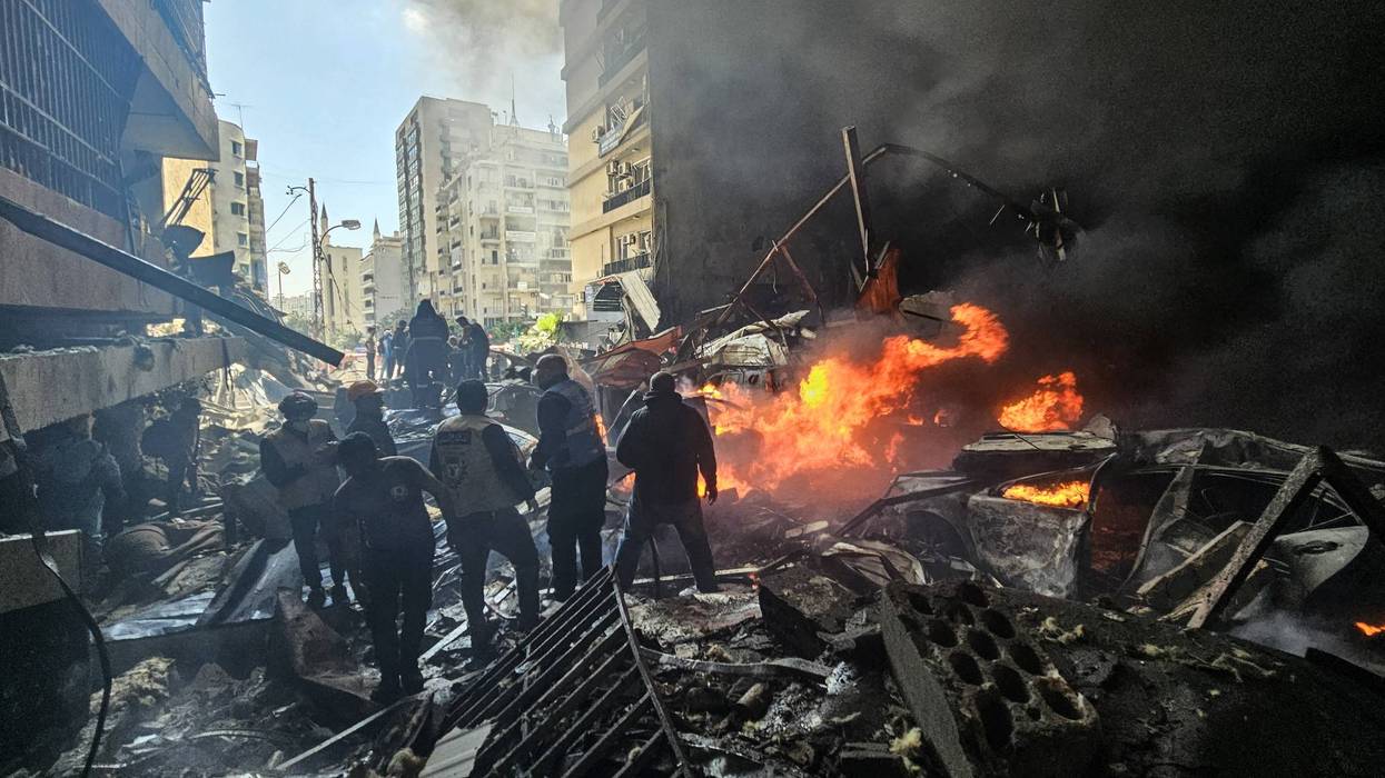 People stand in rubble in Lebanon.