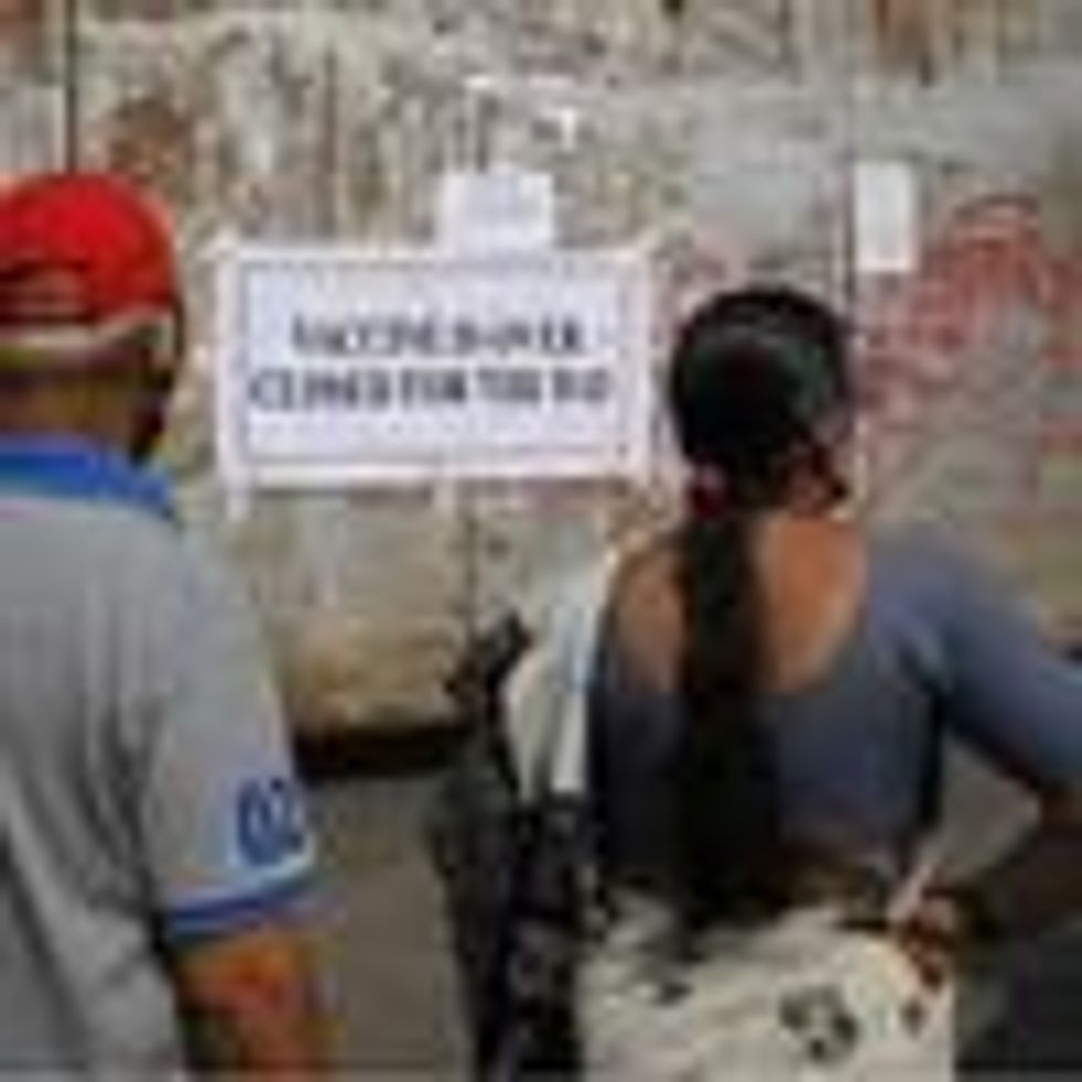 People stand near the gate of a vaccination center with a notice saying