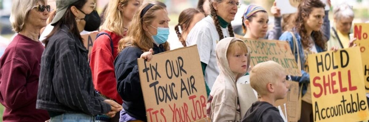 People stand with signs protesting Shell.