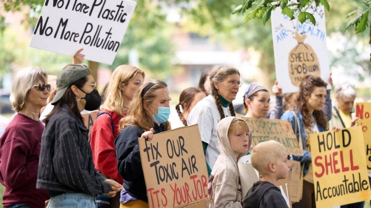 People stand with signs protesting Shell.