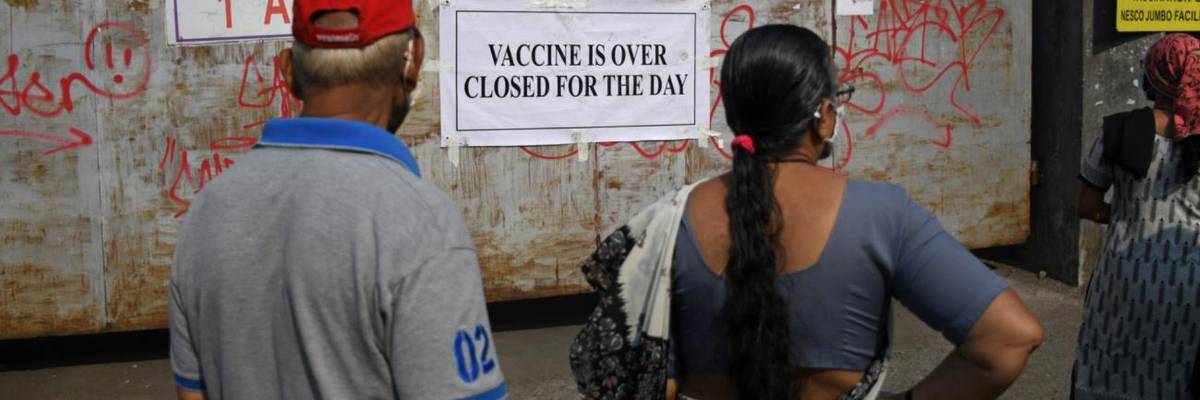 People standing near the gate of a vaccination center.