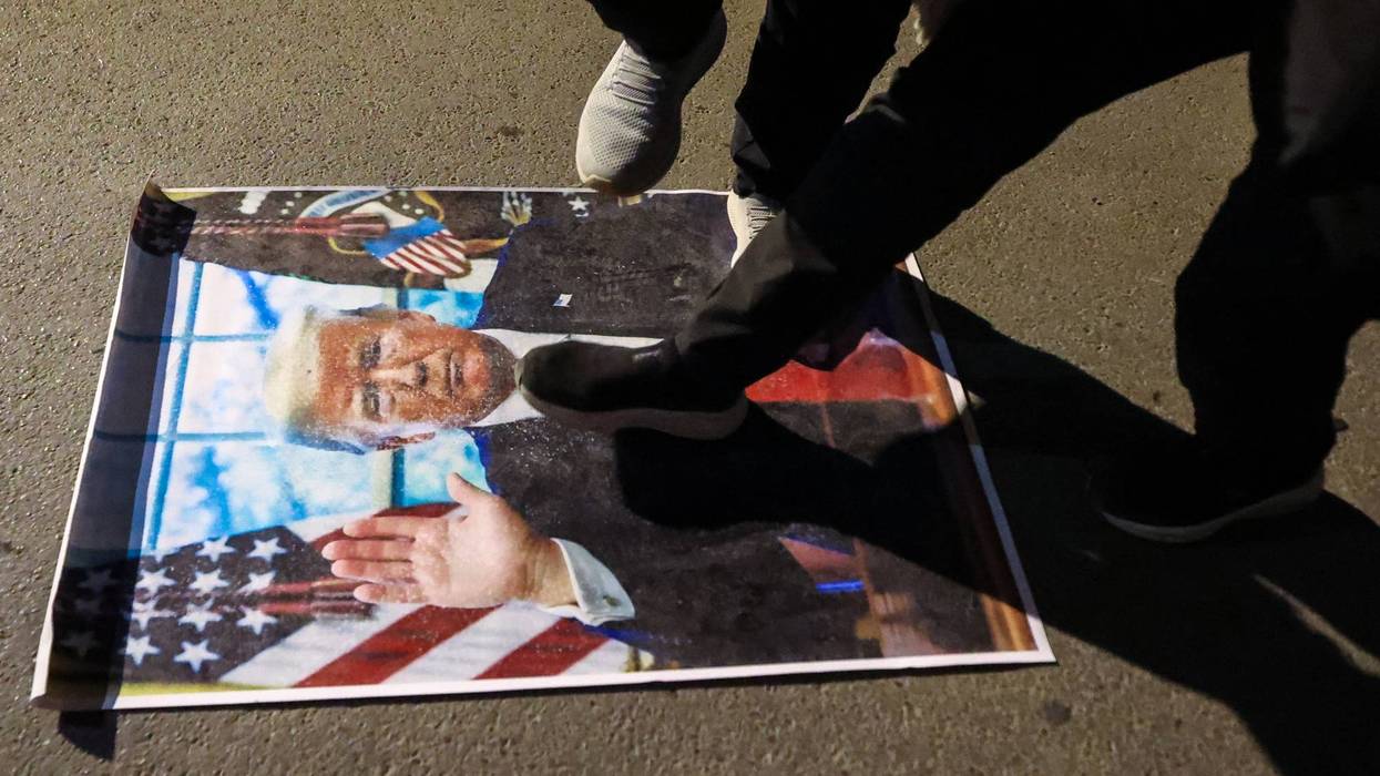 People step on a picture of Trump to protest the Iran War.