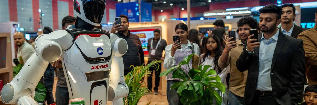 People take photos and videos of a robot at the AI Impact Summit in New Delhi